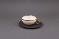 Cieniutka, porcelanowa filiżanka na czarnym spodku